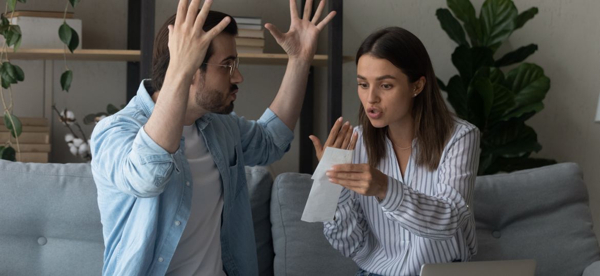 Stressed emotional couple arguing fighting when checking financial papers