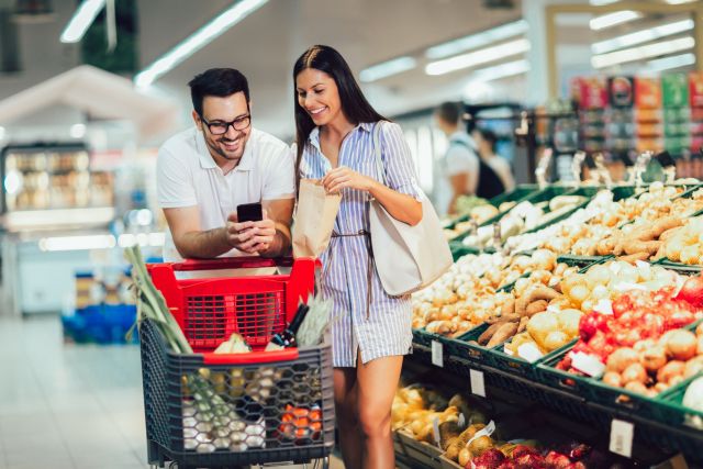 Happy couple buying vegetables at grocery store or supermarket