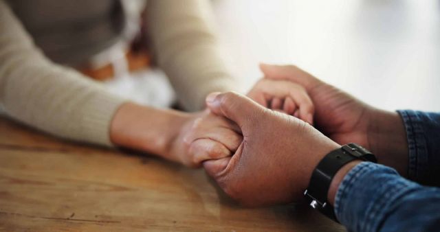 Husband praying for his wife, holding hands